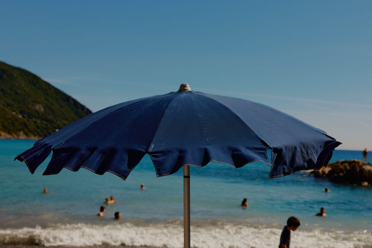 Blue umbrella on a beach with swimmers